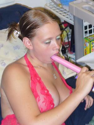 Blondine posiert mit einem Dildo im Bett